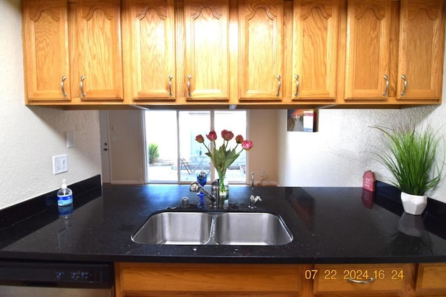 kitchen with black dishwasher, sink, and dark stone counters