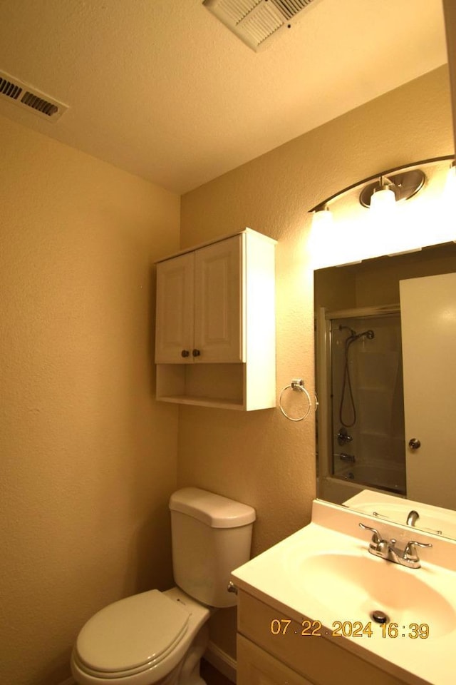 full bathroom with enclosed tub / shower combo, vanity, and toilet