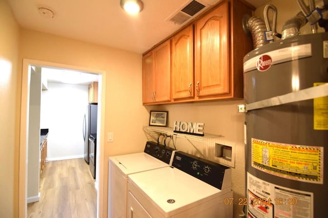 clothes washing area featuring water heater, separate washer and dryer, cabinets, and light hardwood / wood-style flooring