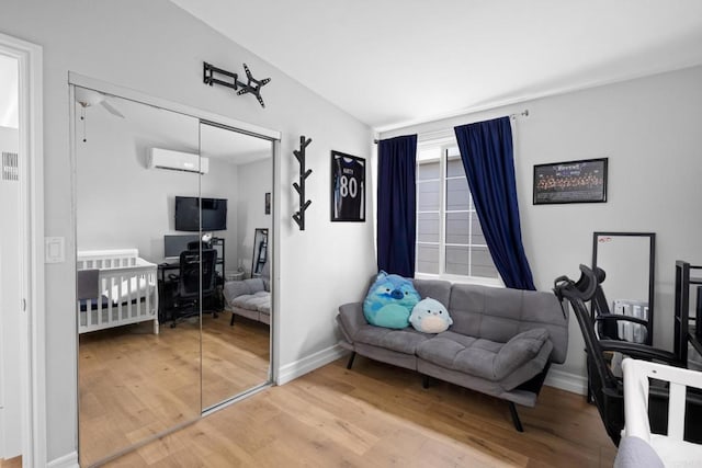 sitting room with wood-type flooring and a wall mounted AC