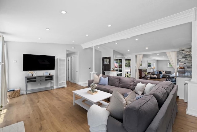 living room with light hardwood / wood-style floors, vaulted ceiling, and decorative columns