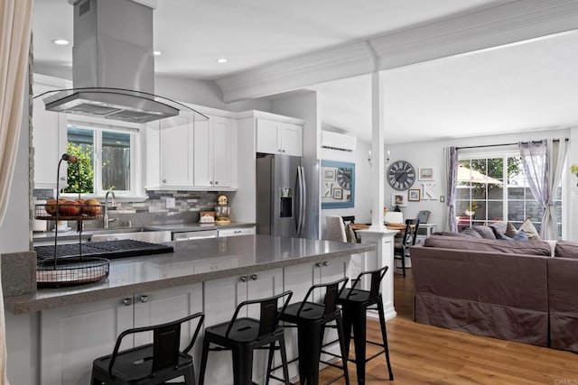 kitchen featuring light hardwood / wood-style floors, island range hood, tasteful backsplash, stainless steel fridge with ice dispenser, and white cabinets