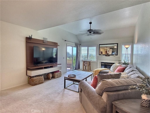 living room with a fireplace, light colored carpet, vaulted ceiling, a textured ceiling, and ceiling fan