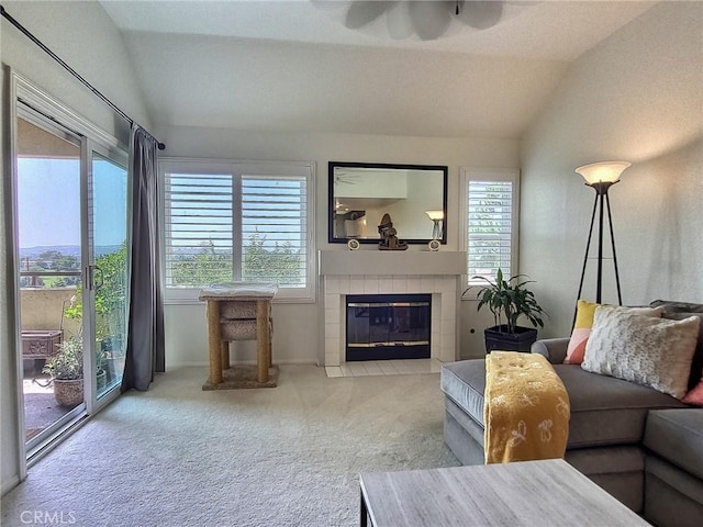 carpeted living area featuring vaulted ceiling, ceiling fan, and a tile fireplace