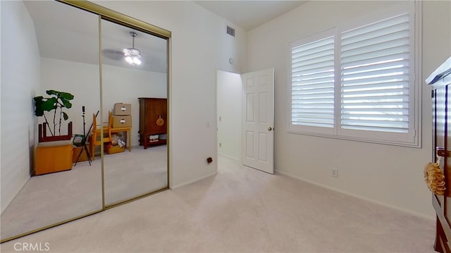 bedroom with light carpet, a closet, visible vents, and baseboards