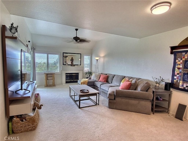 living area featuring a ceiling fan, a glass covered fireplace, carpet flooring, and lofted ceiling