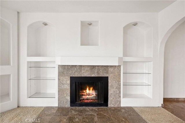 interior details featuring built in features, a tile fireplace, and tile patterned flooring