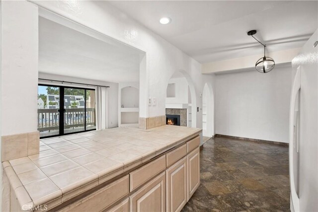 kitchen featuring light brown cabinetry, white refrigerator, french doors, tile patterned floors, and a fireplace