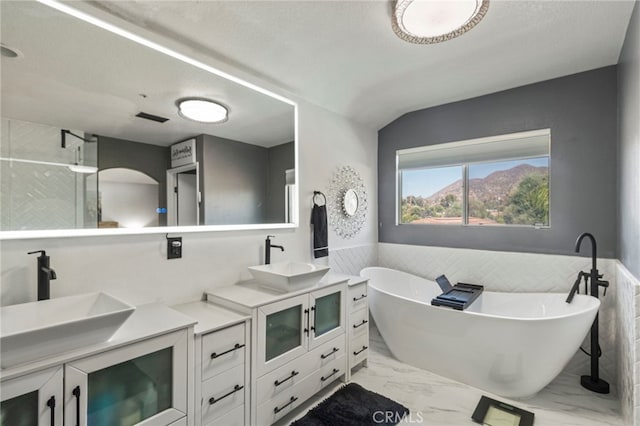 bathroom featuring tile patterned floors, a bathing tub, and dual bowl vanity