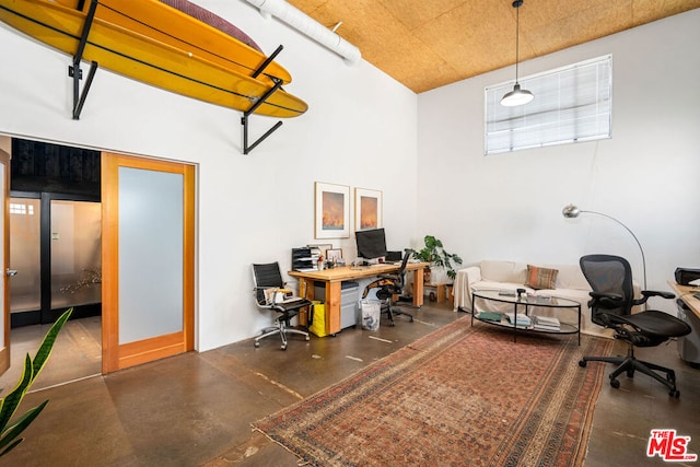 office space featuring concrete flooring and a towering ceiling