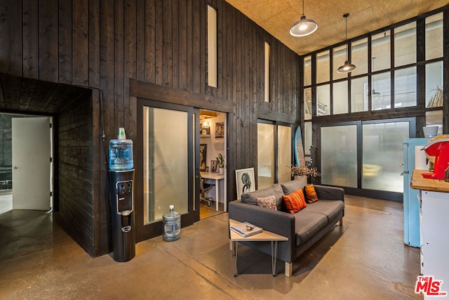 living room with concrete floors, wood walls, and a high ceiling