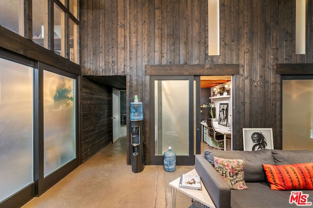 living room with a towering ceiling and wood walls