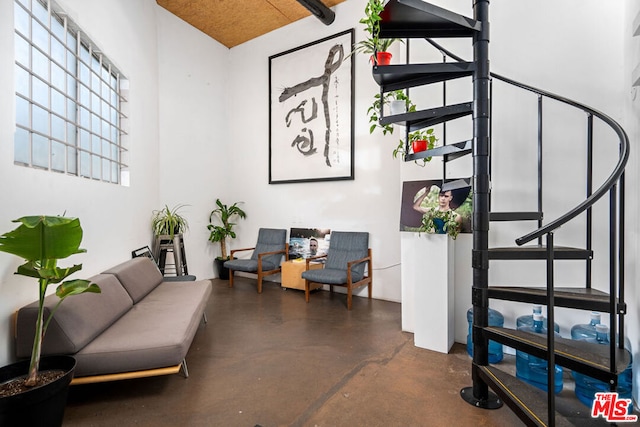 sitting room with a high ceiling and concrete floors