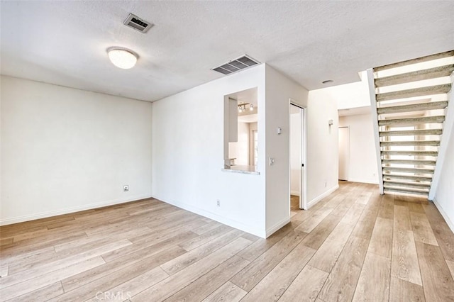 unfurnished room with a textured ceiling and light hardwood / wood-style floors