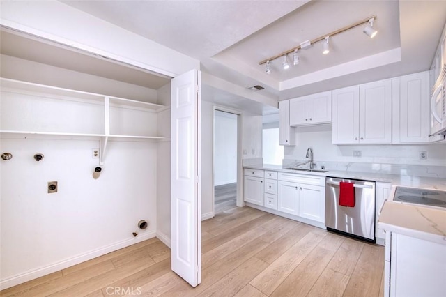 kitchen featuring stainless steel dishwasher, a tray ceiling, sink, light hardwood / wood-style floors, and white cabinetry