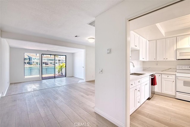 kitchen with white cabinetry, sink, white appliances, and light hardwood / wood-style flooring