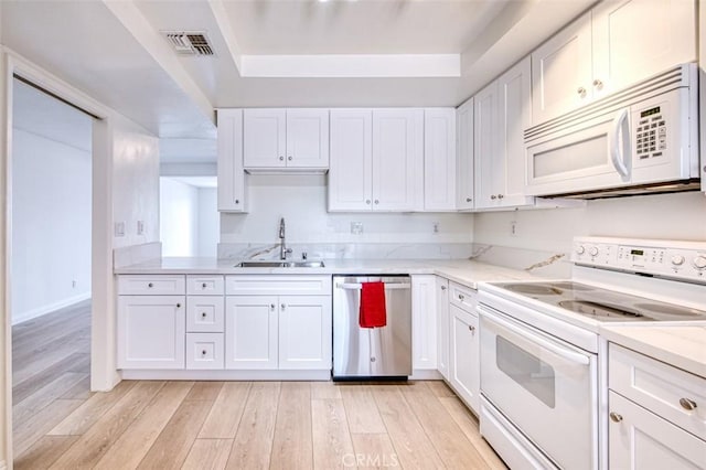 kitchen with white appliances, white cabinets, sink, light hardwood / wood-style flooring, and light stone counters