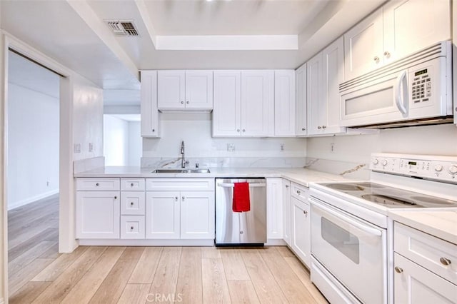16090 Tortola Cir, Huntington Beach, CA 92649 - kitchen with white appliances, a raised ceiling, white cabinetry, light wood-style flooring, and light stone countertops