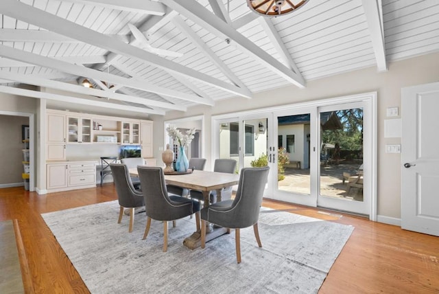 dining room with lofted ceiling with beams, light hardwood / wood-style floors, and french doors