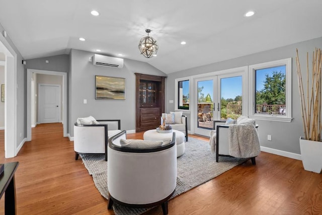 living room featuring lofted ceiling, light wood-type flooring, a chandelier, and a wall unit AC