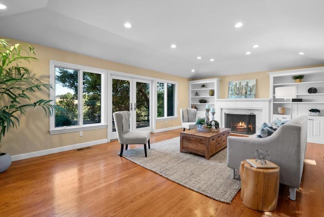 living room with french doors, vaulted ceiling, and light hardwood / wood-style flooring