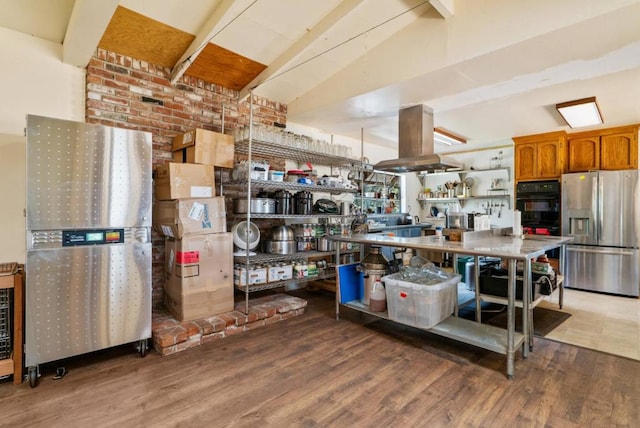 kitchen featuring vaulted ceiling with beams, hardwood / wood-style flooring, stainless steel fridge, and island exhaust hood