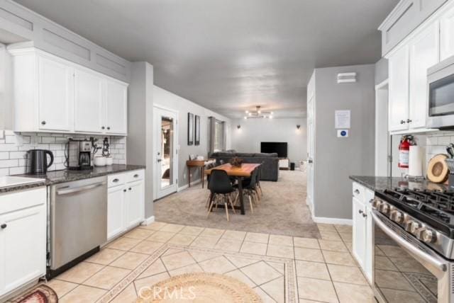 kitchen featuring tasteful backsplash, white cabinetry, appliances with stainless steel finishes, and light tile patterned flooring