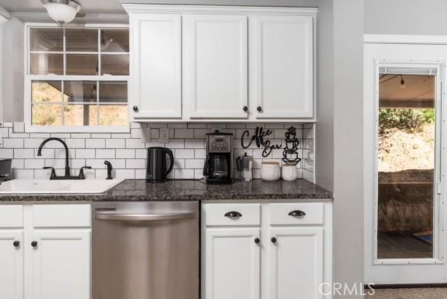 kitchen featuring tasteful backsplash, white cabinetry, dishwasher, sink, and dark stone counters