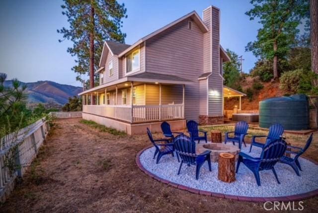 back of property with a mountain view and a fire pit