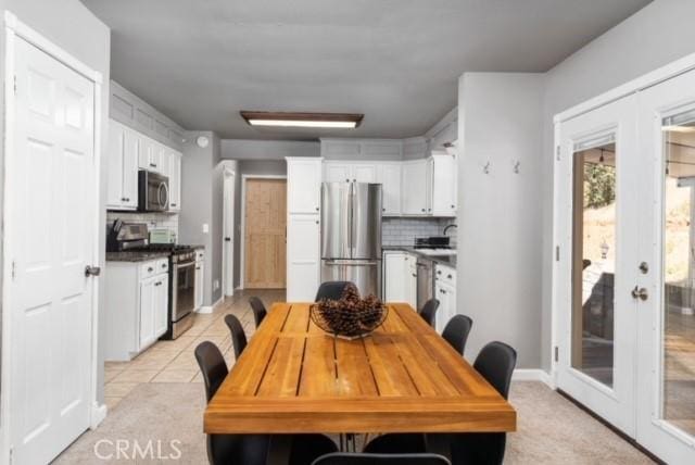 kitchen with french doors, light tile patterned flooring, appliances with stainless steel finishes, decorative backsplash, and white cabinets