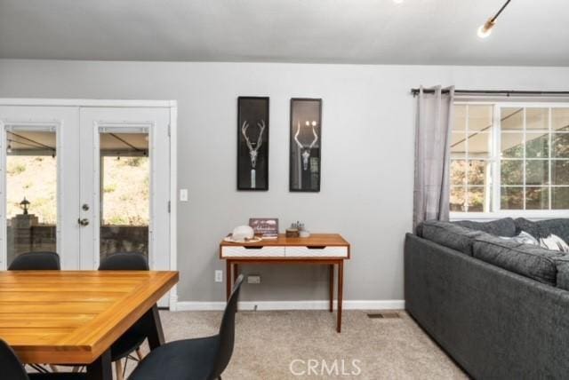 carpeted dining space with french doors