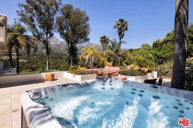 view of swimming pool with a mountain view, a hot tub, and a patio area