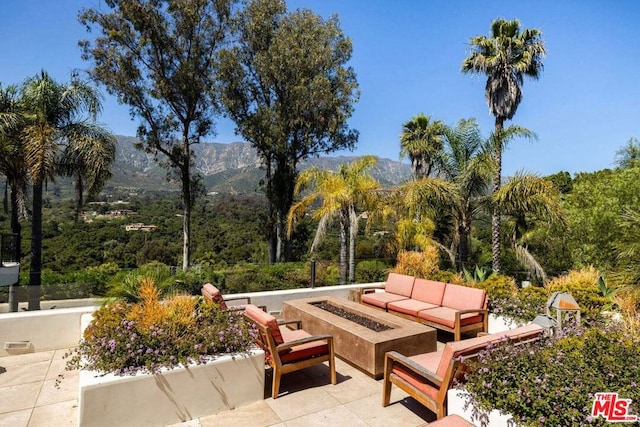 view of patio with a mountain view and an outdoor living space with a fire pit