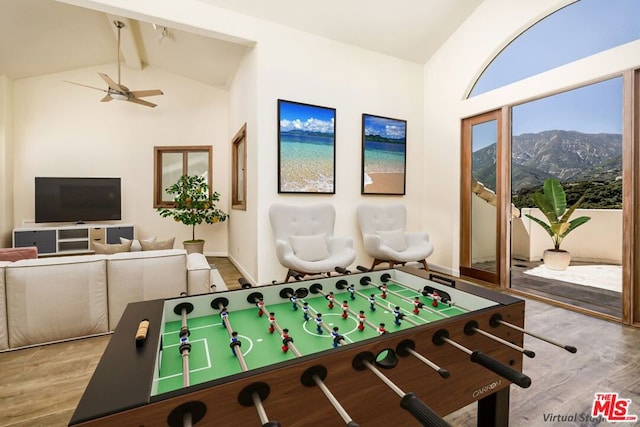 recreation room featuring beam ceiling, ceiling fan, high vaulted ceiling, a mountain view, and light hardwood / wood-style floors