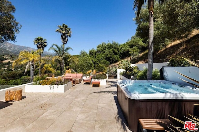 view of patio with a mountain view and a hot tub