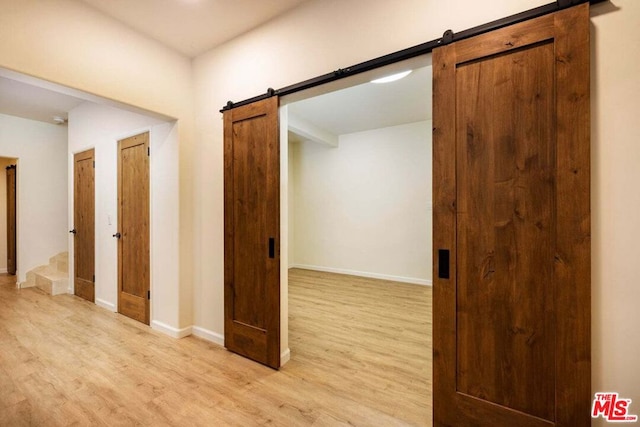 hall with a barn door and light hardwood / wood-style floors