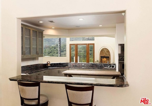 bar with black oven, dark stone counters, and sink