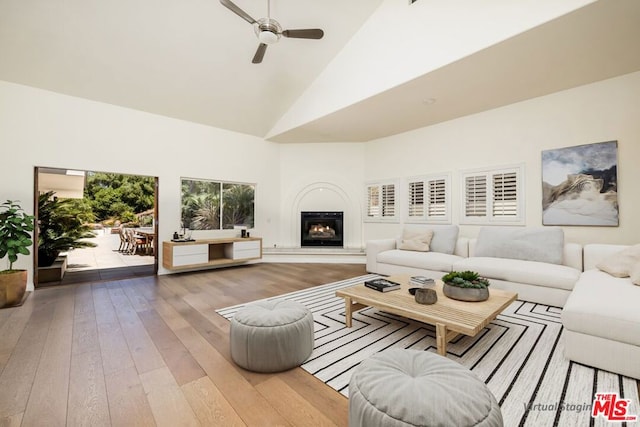 living room with ceiling fan, light wood-type flooring, and high vaulted ceiling