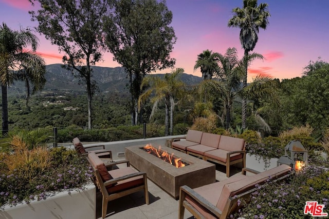 patio terrace at dusk featuring a mountain view and an outdoor living space with a fire pit