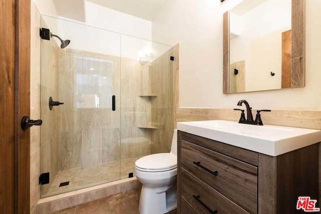 bathroom featuring vanity, toilet, and a shower with shower door