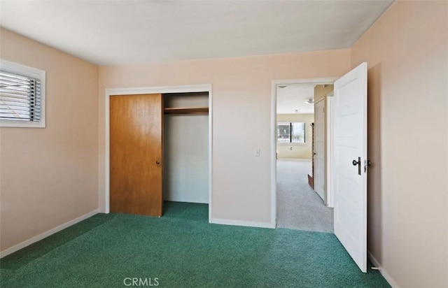 unfurnished bedroom with dark colored carpet and a closet