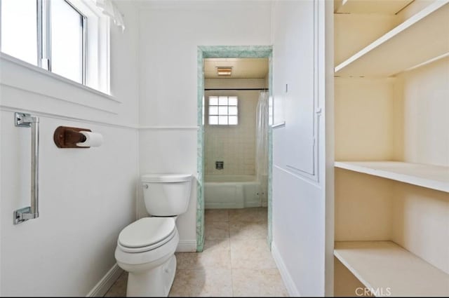 bathroom with shower / tub combo with curtain, tile patterned flooring, and toilet