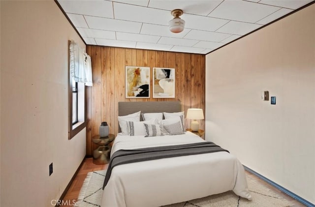 bedroom with light wood-type flooring and wood walls