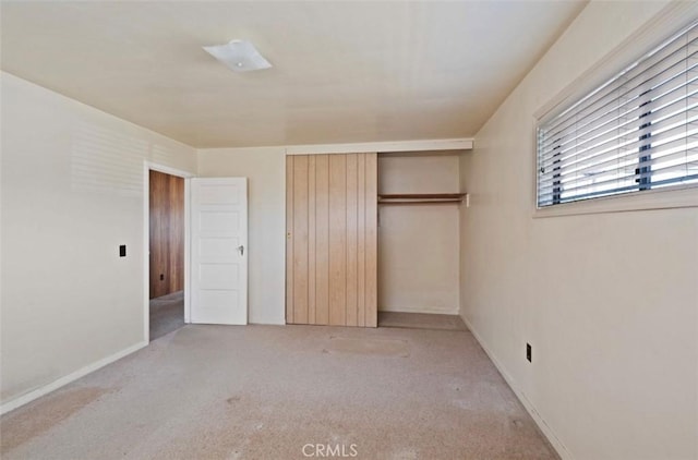 unfurnished bedroom with light colored carpet and a closet