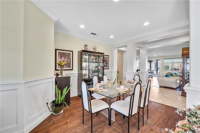 dining space with ornamental molding, decorative columns, and hardwood / wood-style floors