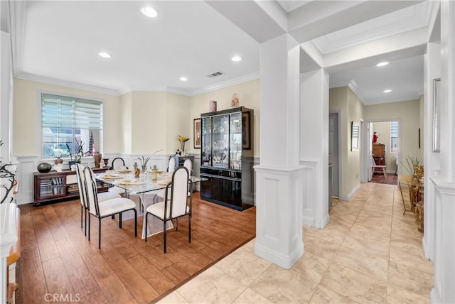 dining room with ornate columns, ornamental molding, a wealth of natural light, and light hardwood / wood-style flooring