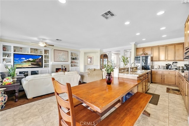 dining area featuring built in shelves, sink, light tile patterned floors, ornamental molding, and ceiling fan