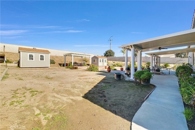 view of yard featuring a pergola, a patio area, ceiling fan, and a storage shed