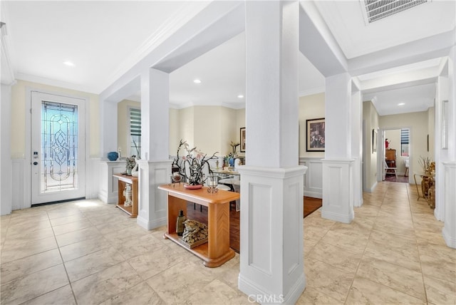 entryway with crown molding, decorative columns, and a wealth of natural light