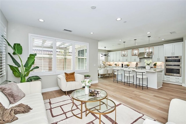 living area with light wood finished floors, baseboards, visible vents, and recessed lighting